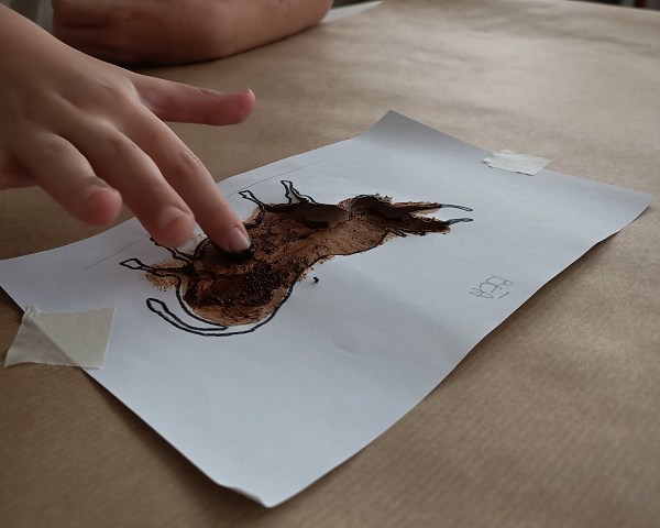 Foto della mano di un bambino che dipinge con un dito un bisonte