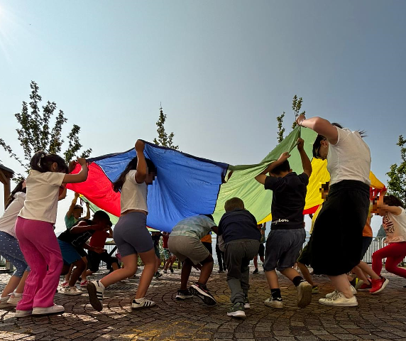 studenti e maestre sotto il telo colorato